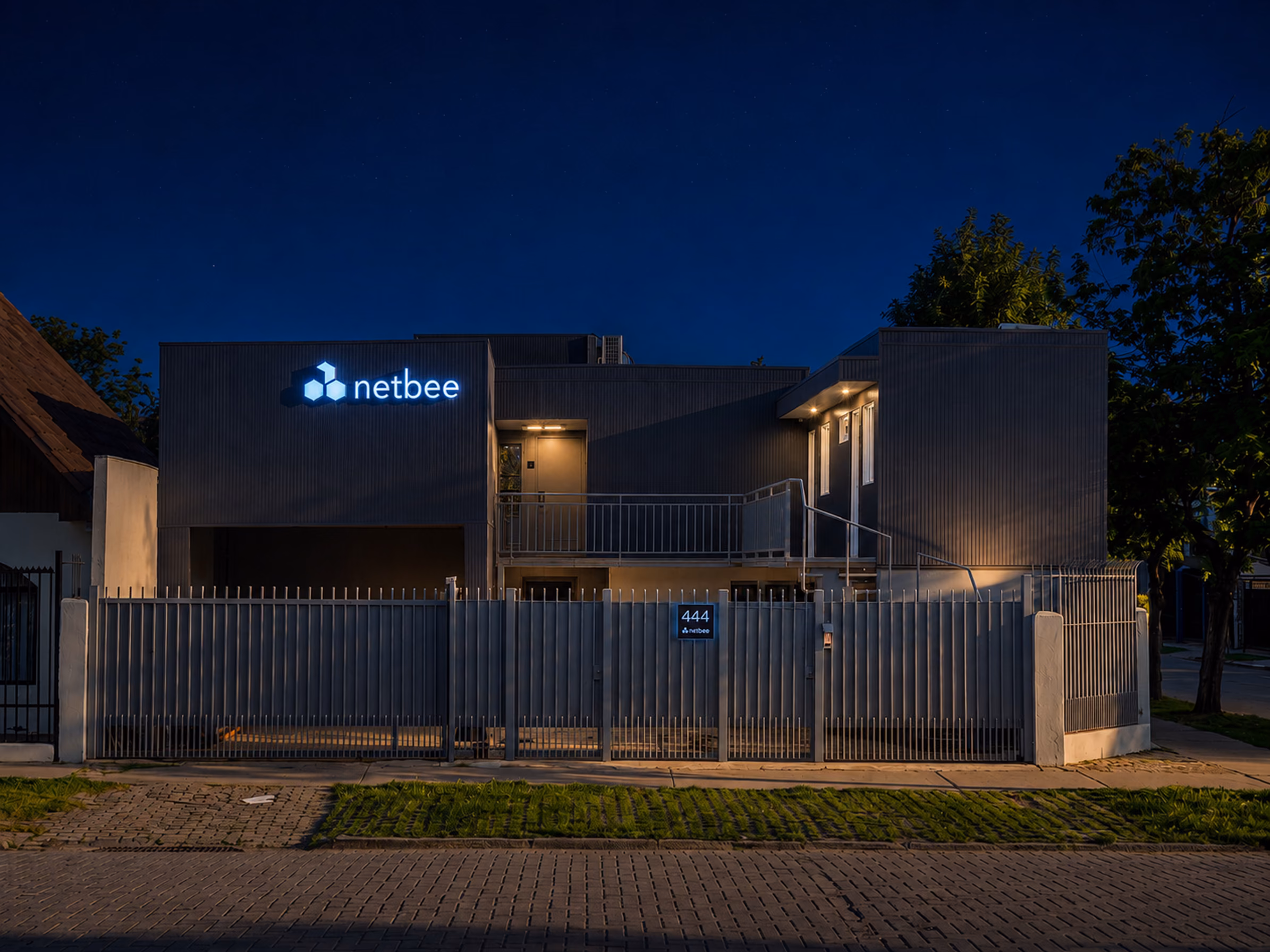 La misma fachada de noche, con el letrero y la iluminación interior encendidos